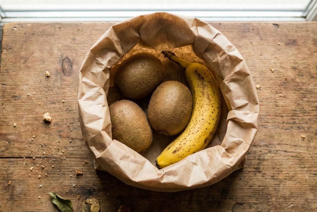 Technique du sac kraft avec une banane pour accélérer le mûrissement des kiwis